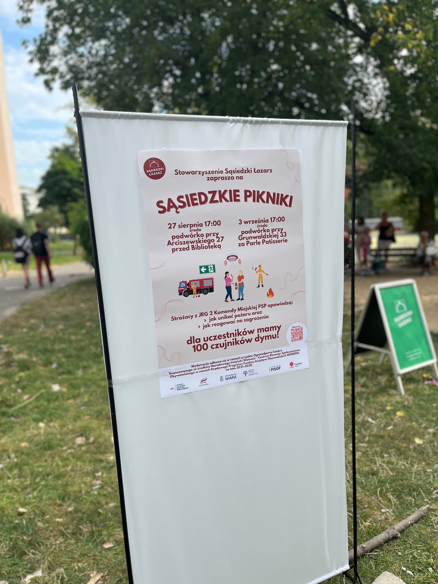 Plakat wydarzenia „Sąsiedzkie Pikniki” na tablicy ogłoszeń w parku