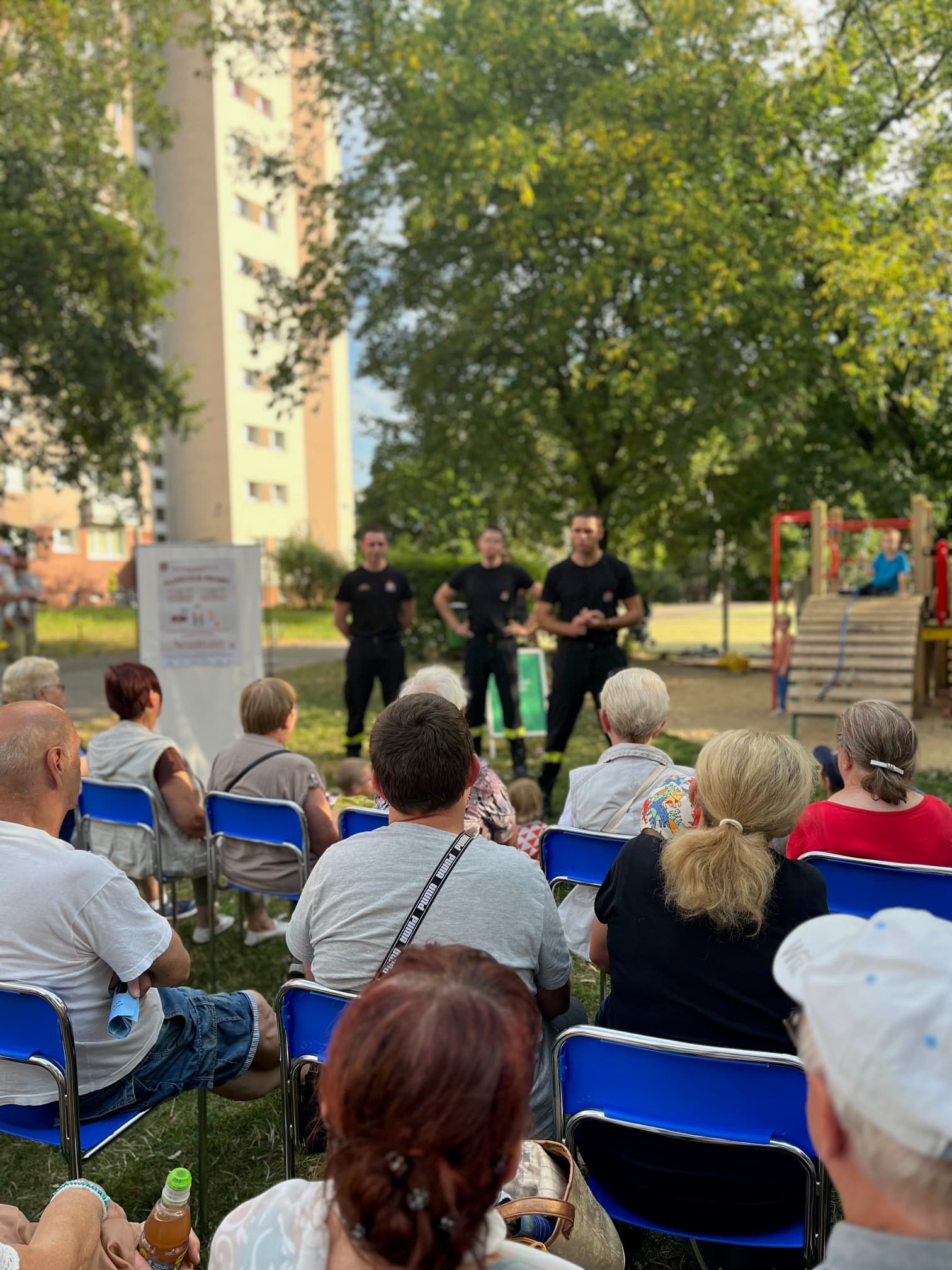 Strażacy prowadzą pokaz dla mieszkańców na osiedlowej polanie