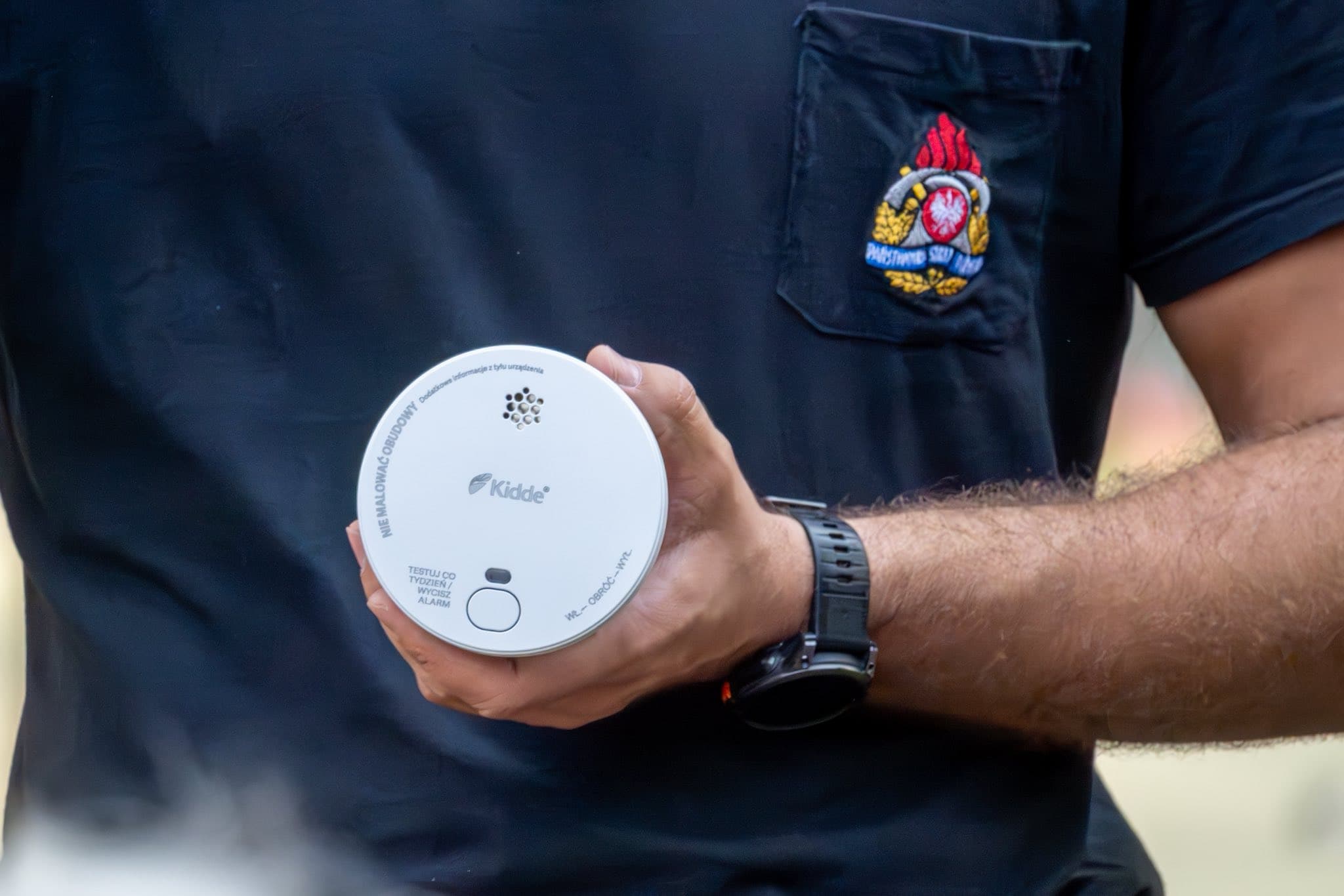 Strażak trzyma czujnik dymu – prezentacja sprzętu przeciwpożarowego